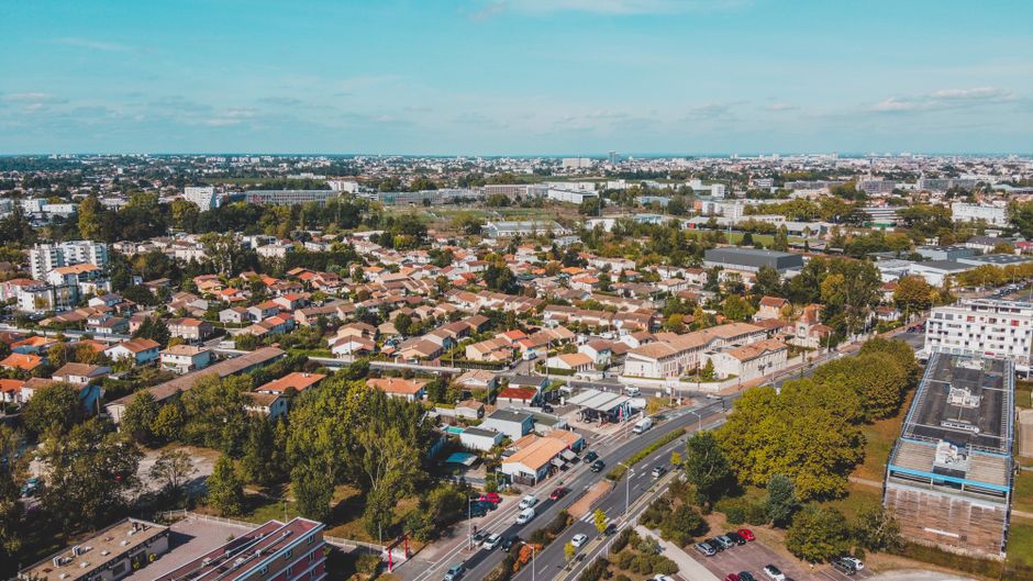 A well-maintained urban garden in De Beauvoir Town featuring neatly edged flower beds with a variety of blooming plants and greenery. The garden includes lush grass pathways, mulched soil, and trimmed